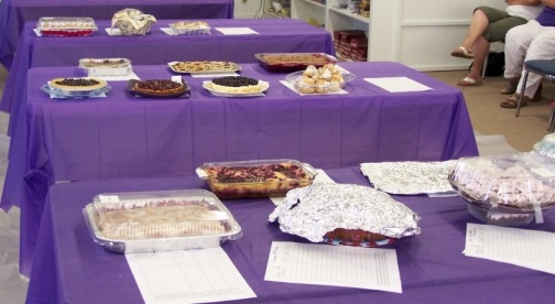 A table with various desserts covered in foil and labels.