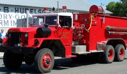 Vintage red fire truck parked outdoors on a sunny day.