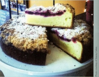 Slice of crumb-topped cake with a fruit filling on a plate.