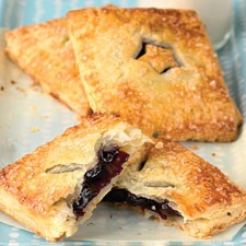 Freshly baked pastries with a dark fruit filling oozing out.