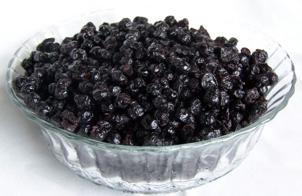 A glass bowl filled with dried black currants.