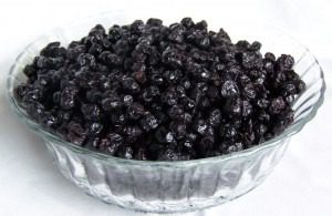 A glass bowl filled with dried black currants.
