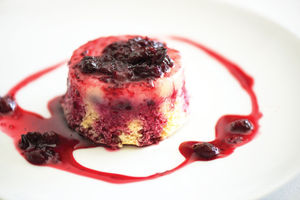 A dessert topped with berry sauce on a white plate.