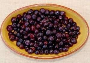 Oval dish with dark berries on burlap.