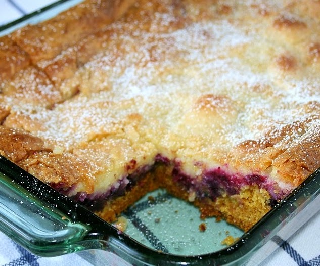 A homemade berry cobbler with a golden crust in a glass baking dish.