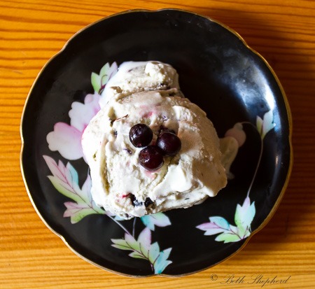 A scoop of cookies and cream ice cream with blueberries on a floral plate.