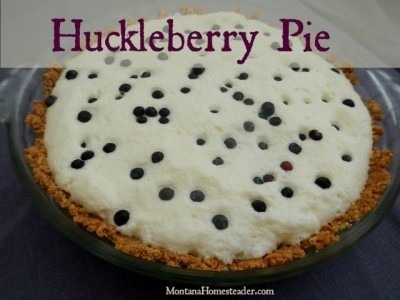 A huckleberry pie topped with whipped cream and fresh huckleberries.