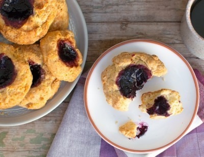 Homemade cookies with jam centers on a plate and one on a smaller dish.