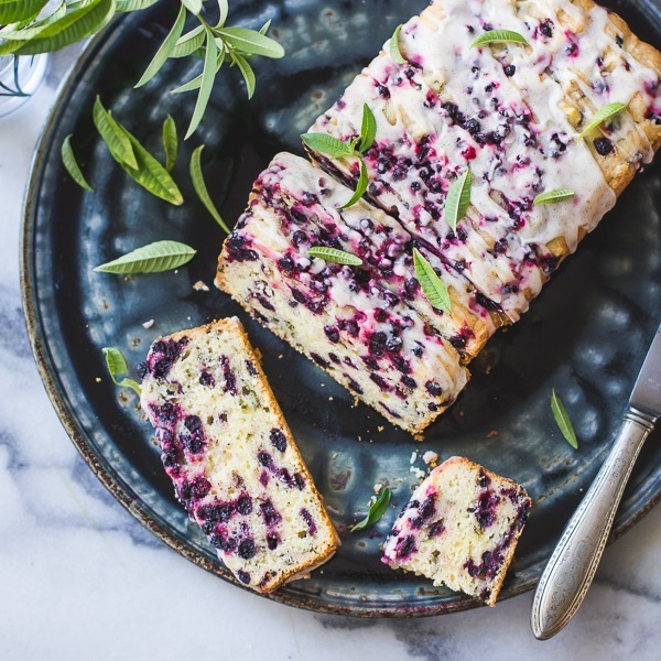 Rustic berry loaf on a dark plate with herbs and a knife.