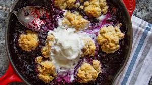 Blueberry cobbler topped with whipped cream in a skillet.