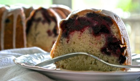 A slice of berry marble bundt cake on a plate with a fork.