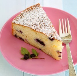 Slice of blueberry cheesecake dusted with powdered sugar on a pink plate.