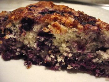 A slice of moist blueberry cake with a crumb topping.