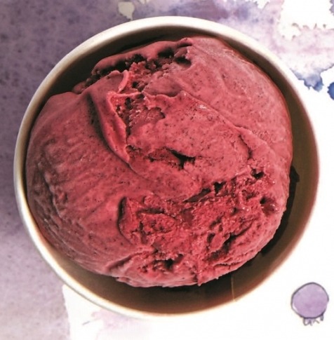 A bowl of deep red beetroot hummus with cumin seeds on top.