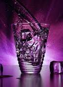 A crystal-clear glass filled with ice cubes and a purple light background.