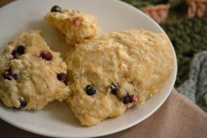 Freshly baked scones with berries on a white plate.