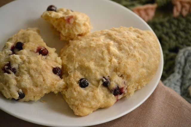 Freshly baked scones with berries on a white plate.