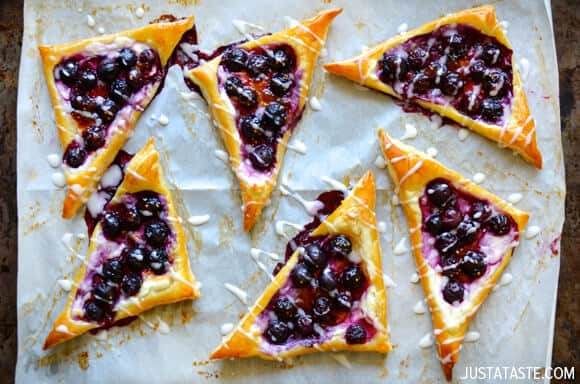 Triangular blueberry tarts with a golden crust on parchment paper.