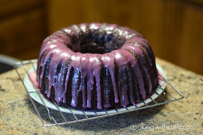 A shiny, purple-glazed bundt cake cooling on a wire rack.
