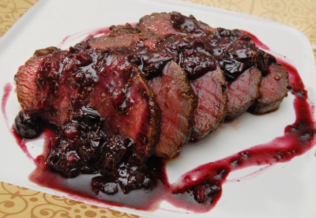 Sliced roast beef with a rich berry sauce drizzled on top.