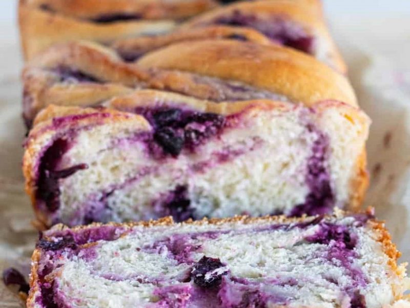 Close-up of a sliced blueberry swirl bread loaf showing its soft texture and vibrant berries.
