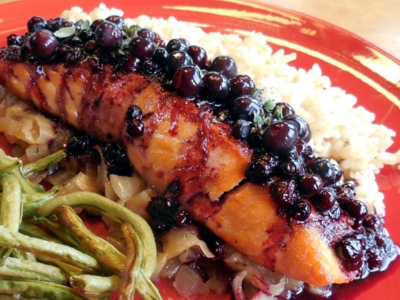 Grilled salmon topped with a blueberry glaze, served with rice and green beans.