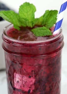 A jar of homemade berry jam garnished with fresh mint leaves.