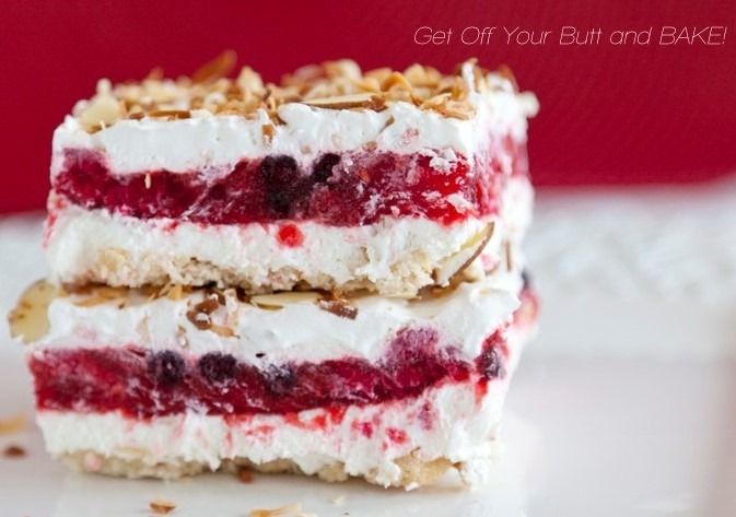 Close-up of layered dessert bars with cream, berry filling, and toasted topping.