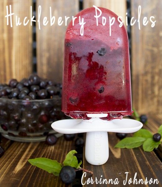 Homemade blueberry popsicles with fresh blueberries in the background.